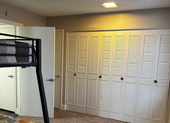 a bedroom with a bunk bed and many closet doors
