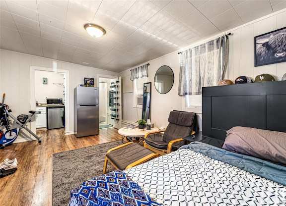 a bedroom with a bed and a refrigerator in a small room