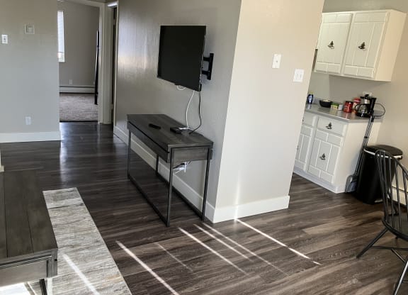 a living room with a tv and a kitchen with white cabinets