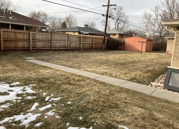 a backyard with a wooden fence and a sidewalk