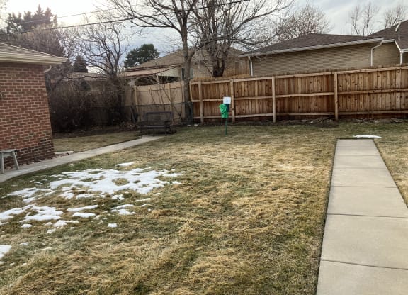 a backyard with a fence and a yard with snow on the ground