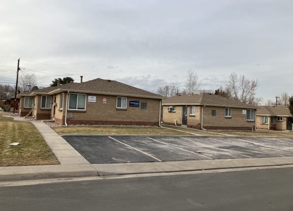 an empty parking lot in front of a brick house