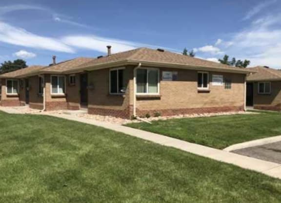 a brown brick house with a lawn and a sidewalk