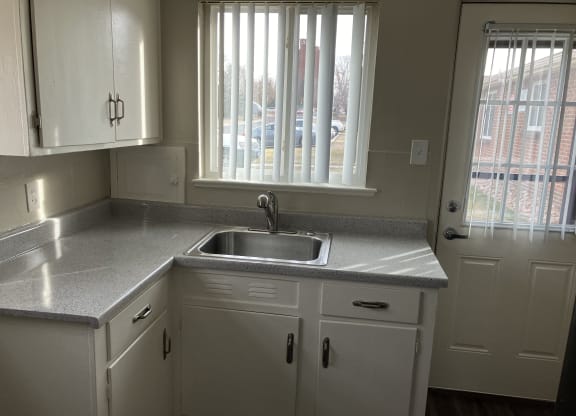 an empty kitchen with white cabinets and a sink