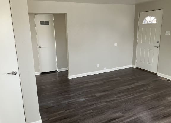 an empty living room with wood floors and white walls