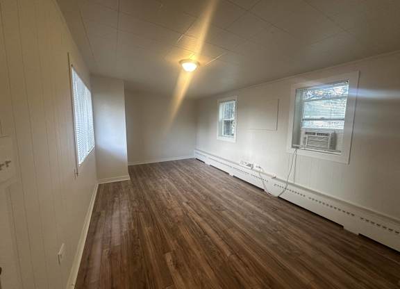 an empty living room with white walls and wood floors