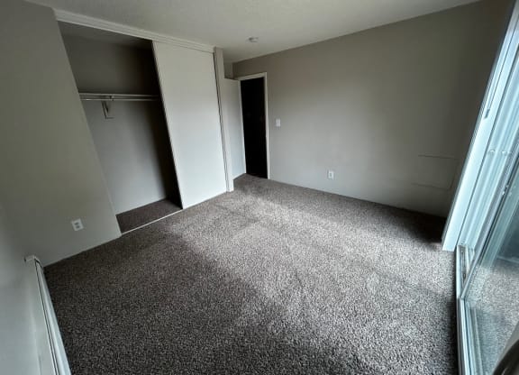 a room with a carpeted floor and a door to a closet