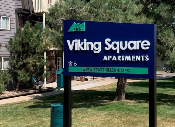 a sign for viking square apartments in front of a house