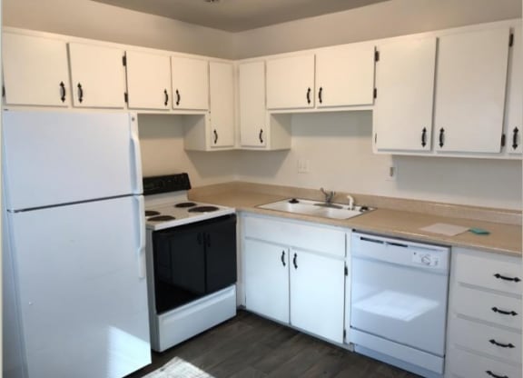 an empty kitchen with white cabinets and black and white appliances