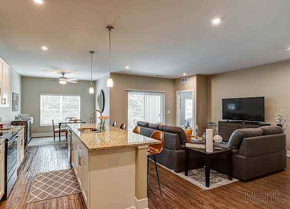 A kitchen with a refrigerator, sink, and a counter with a chair and a table.