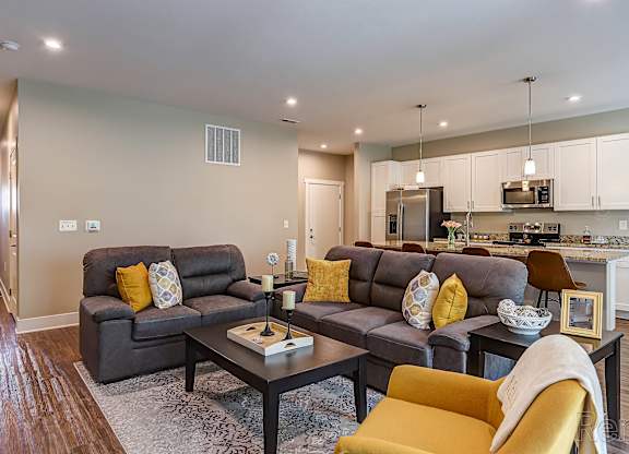 A modern living room with grey couches and yellow pillows.
