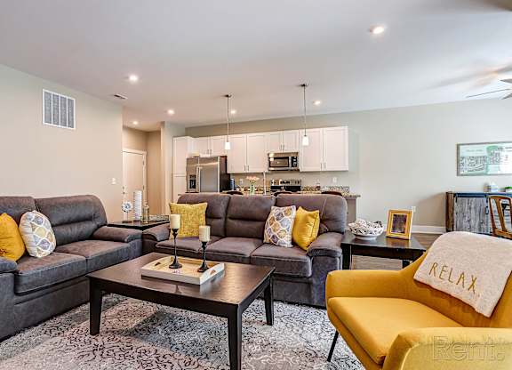 A living room with grey couches and a yellow chair.