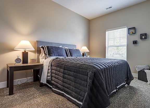 A bedroom with a large bed and two lamps on the side tables.