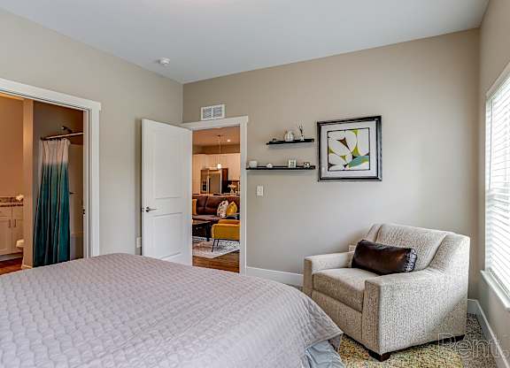 A bedroom with a large bed, a chair, and a picture on the wall.