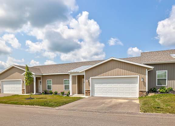 A house with a brown roof and two white garage doors.
