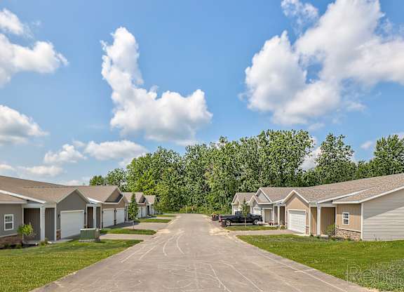 A residential street with houses on both sides and a truck parked on the right.
