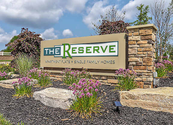 A sign for "The Reserve Apartments & Single Family Homes" is displayed in front of a landscaped area.
