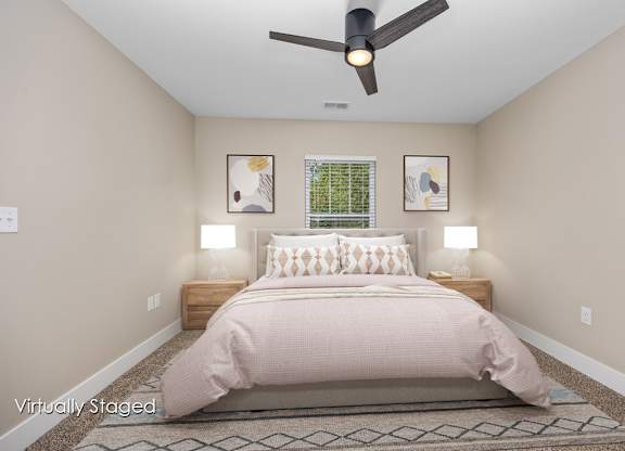 A bedroom with a bed, two lamps, and a ceiling fan.