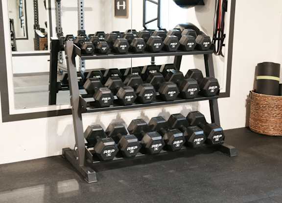 A rack of black dumbbells in a gym.