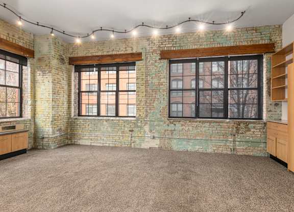 A room with a brick wall and string lights on the ceiling.