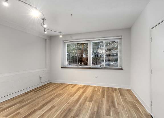 A room with wooden flooring and a window with blinds.