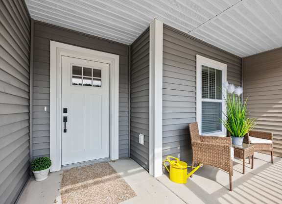 A small porch with a white door and a yellow bucket.