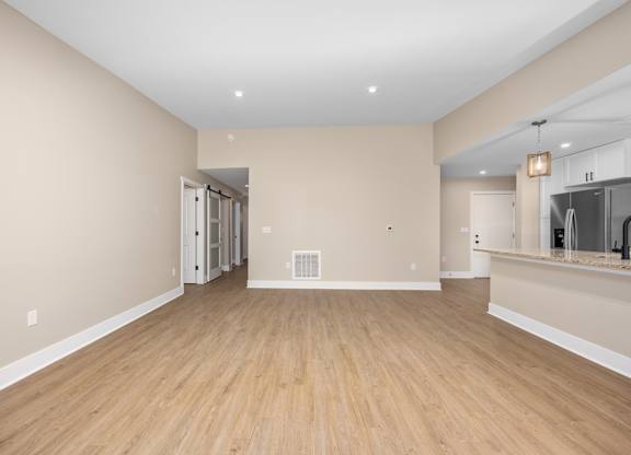A spacious room with wooden flooring and a large mirror on the wall.