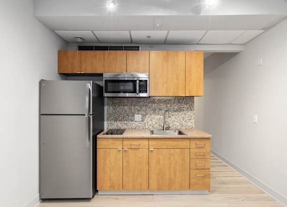 A kitchen with a refrigerator, microwave, and sink.