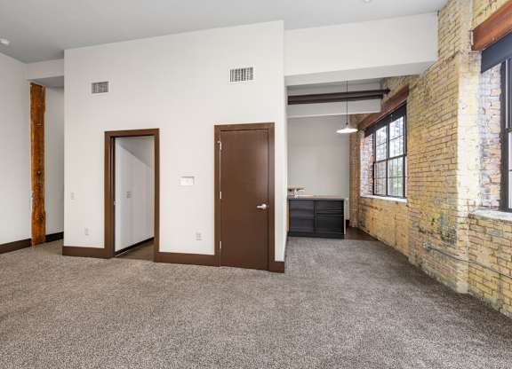 A room with a carpeted floor and a brick wall.