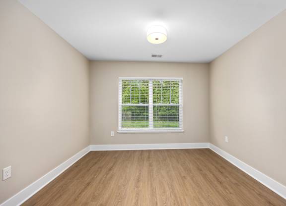 A room with a window and wooden flooring.