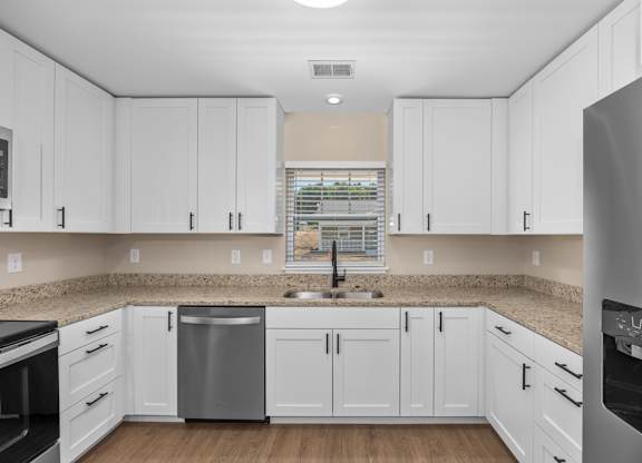 A kitchen with white cabinets and a granite countertop.