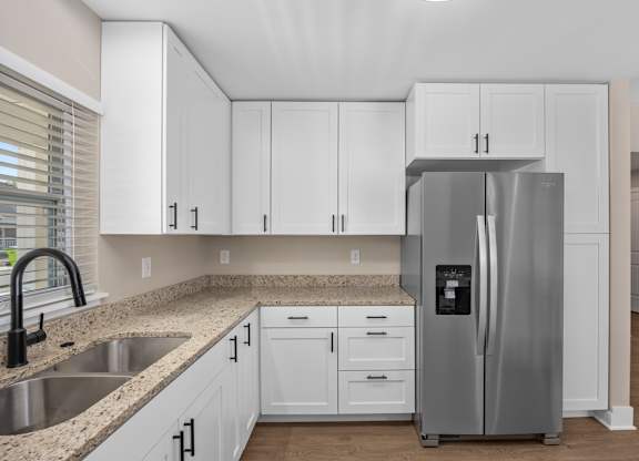 A kitchen with white cabinets and a stainless steel refrigerator.