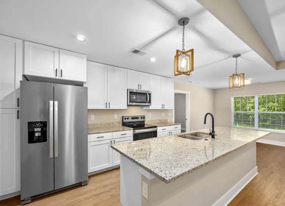 A modern kitchen with a granite countertop and stainless steel appliances.