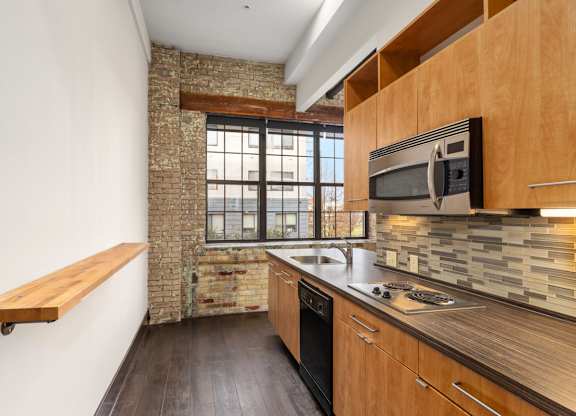 A kitchen with wooden cabinets and a brick wall.
