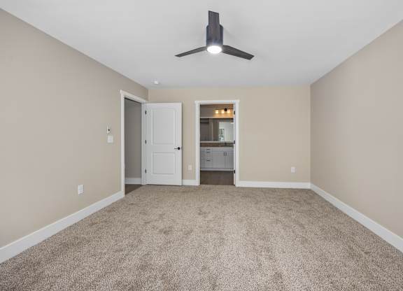 A room with a carpeted floor and a ceiling fan.