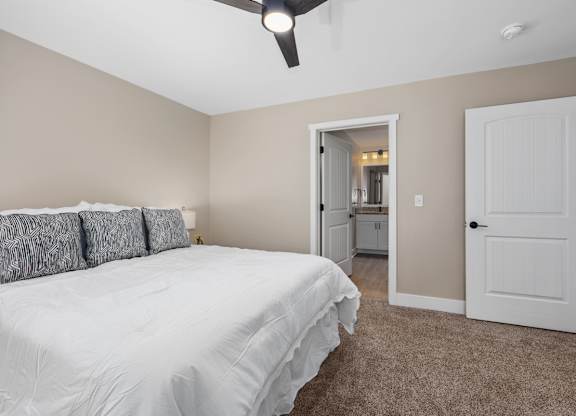 A bedroom with a white bed and a ceiling fan.