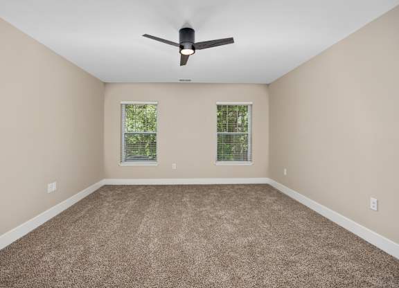 A room with a ceiling fan and carpeted floor.
