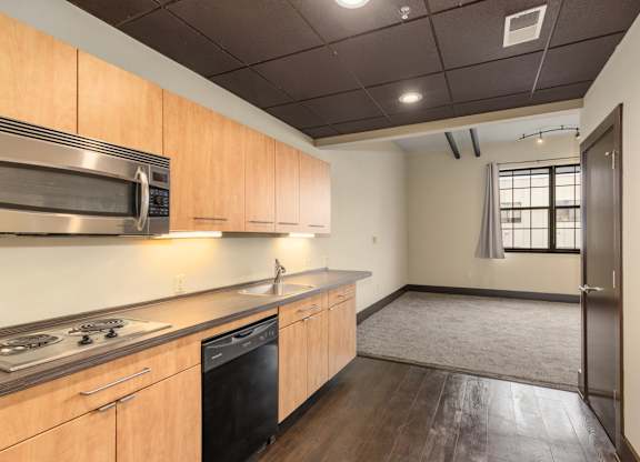 A kitchen with wooden cabinets and a black dishwasher.