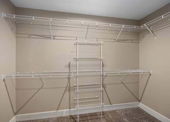 A large, empty walk-in closet with a carpeted floor and metal shelving.