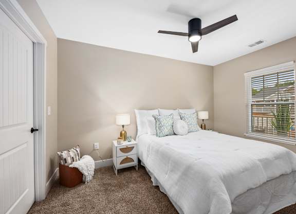 A bedroom with a bed, nightstands, and a ceiling fan.