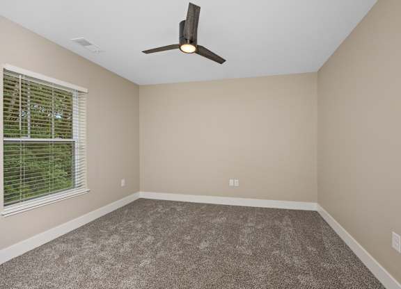 A room with a ceiling fan and carpeted floor.