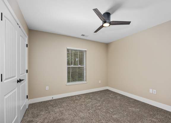 A room with a ceiling fan and a window with blinds.