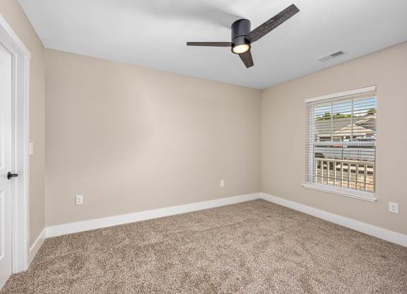 A room with a ceiling fan and a window with blinds.