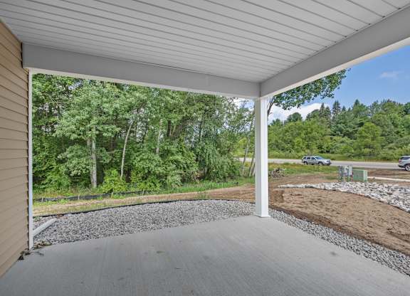A covered porch with a gravel floor and a white ceiling.