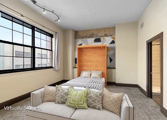 A bedroom with a large bed and a window with blinds.