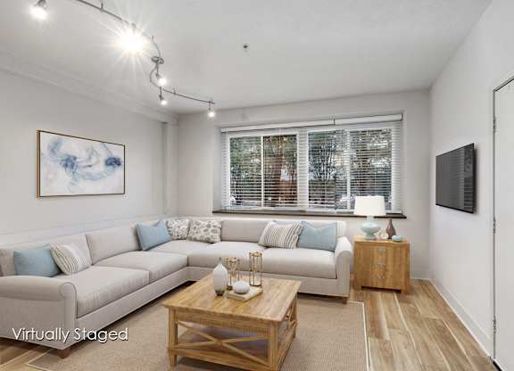 A living room with a couch, coffee table, and a painting on the wall.