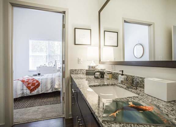 A bathroom with a sink, mirror, and a window.