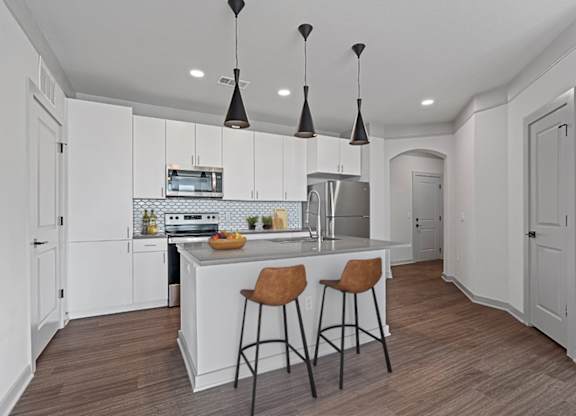 A kitchen with a white island and brown bar stools.