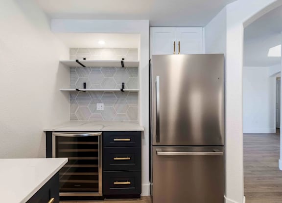 A modern kitchen with a stainless steel refrigerator and black drawers.