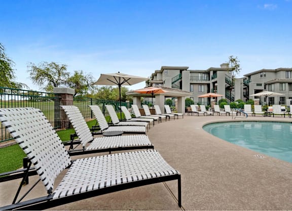 A row of sun loungers are arranged on a patio.